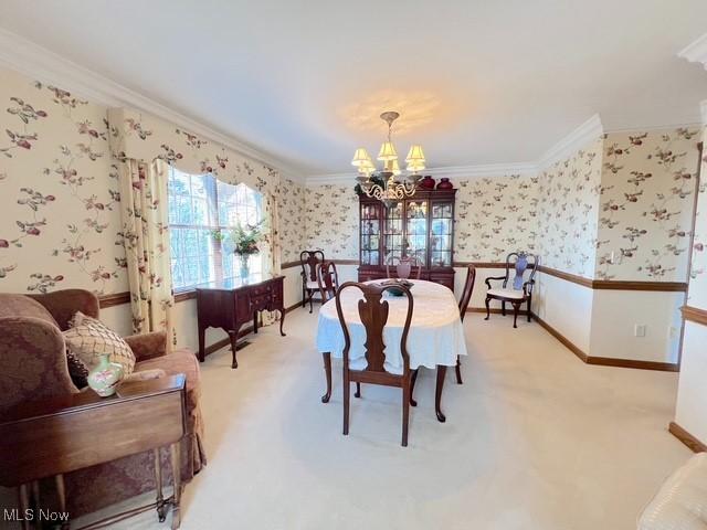 dining room with crown molding, baseboards, a notable chandelier, and wallpapered walls