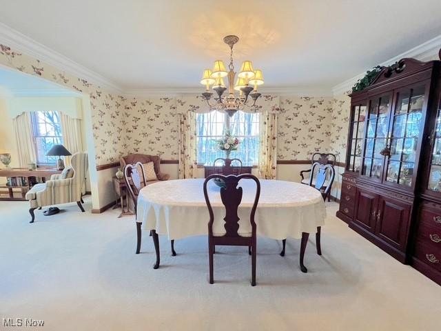 dining area featuring ornamental molding, a chandelier, light colored carpet, and wallpapered walls