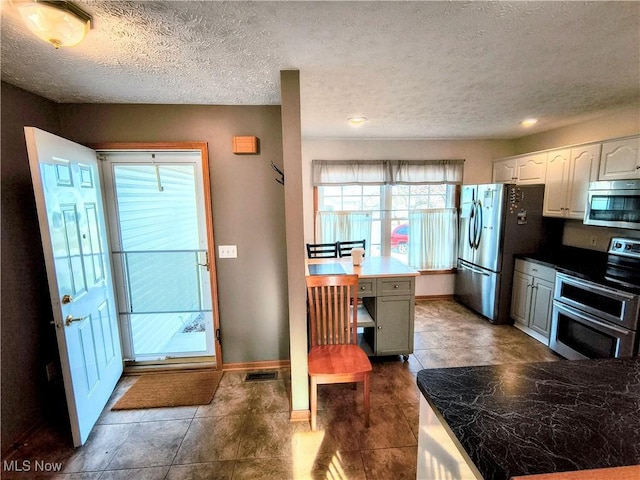 kitchen featuring baseboards, stainless steel appliances, visible vents, and white cabinetry