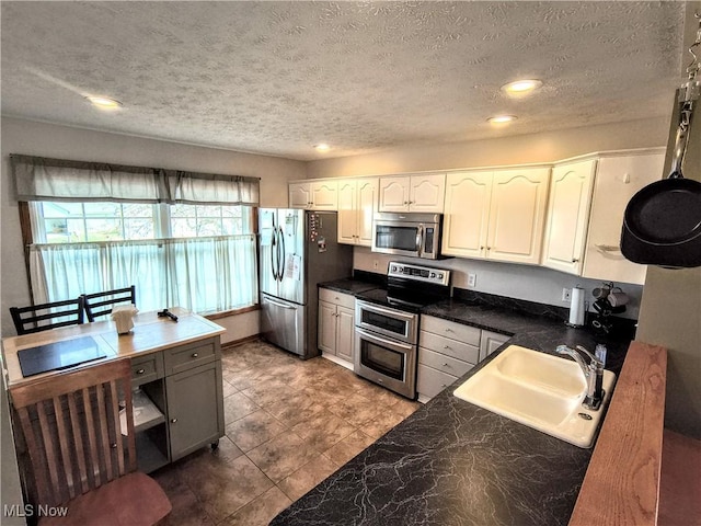 kitchen featuring a textured ceiling, recessed lighting, stainless steel appliances, a sink, and white cabinets