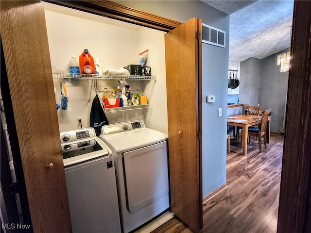 laundry room featuring laundry area, visible vents, washer and clothes dryer, wood finished floors, and a textured ceiling