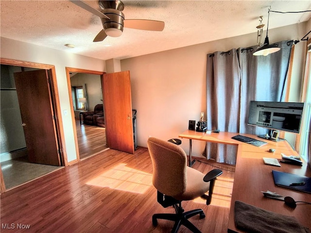 office area with baseboards, a textured ceiling, a ceiling fan, and wood finished floors