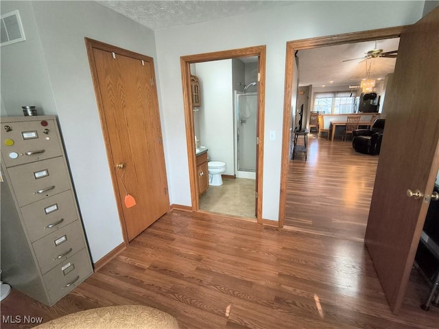 hall with visible vents, baseboards, and wood finished floors