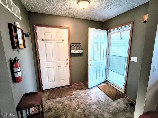 entryway featuring visible vents, a textured ceiling, and baseboards