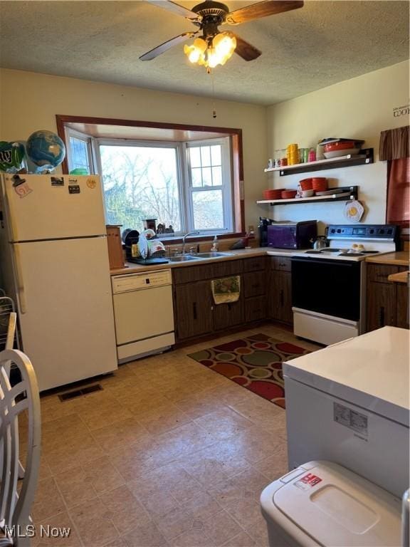 kitchen featuring a textured ceiling, white appliances, a sink, visible vents, and a ceiling fan