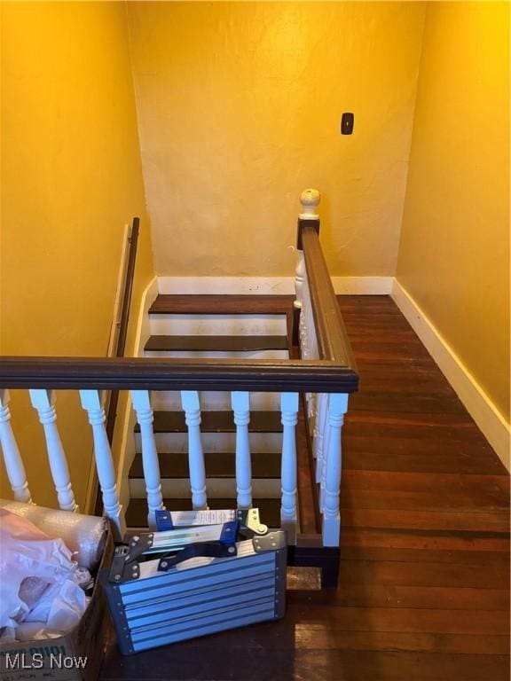 stairway featuring baseboards and wood finished floors