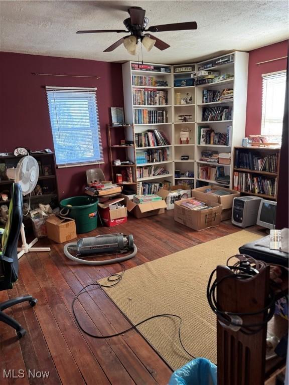 interior space with a textured ceiling, ceiling fan, and hardwood / wood-style flooring