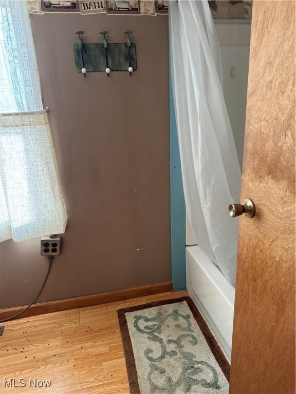 bathroom with shower / bath combination with curtain, baseboards, and wood finished floors