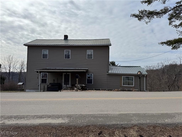 rear view of property with metal roof and a chimney