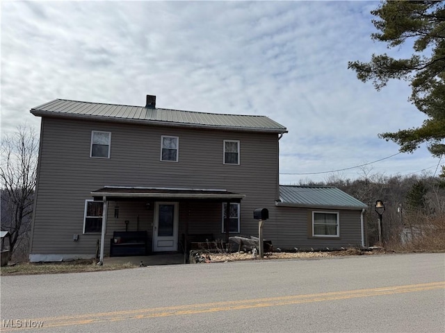 view of front facade featuring metal roof, a porch, and a chimney