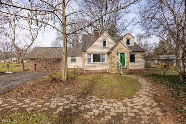 cape cod-style house featuring entry steps, roof with shingles, and a chimney