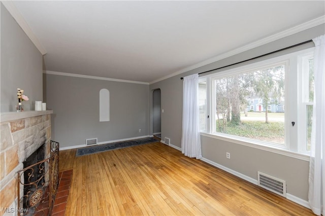 unfurnished living room with light wood-type flooring, baseboards, visible vents, and a stone fireplace