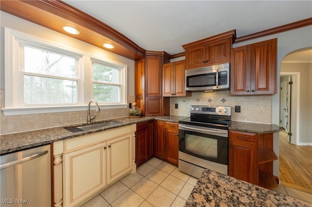 kitchen with dark stone countertops, appliances with stainless steel finishes, decorative backsplash, and a sink