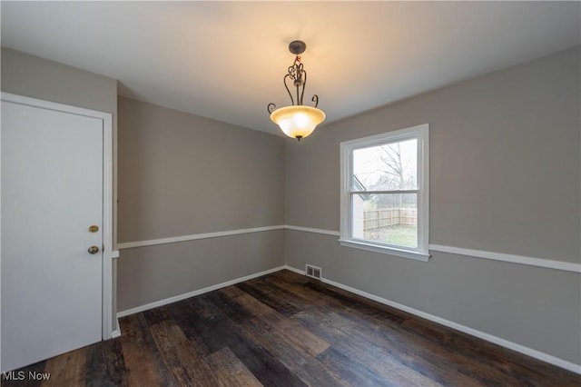 unfurnished room featuring baseboards, visible vents, and dark wood-type flooring