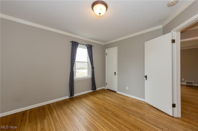 unfurnished room with light wood-style floors, visible vents, ornamental molding, and baseboards