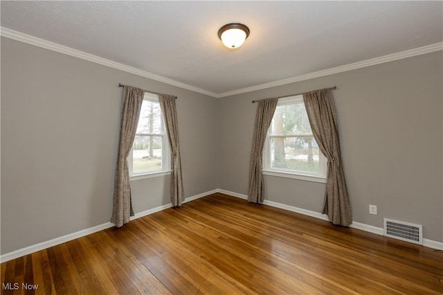 empty room with hardwood / wood-style flooring, baseboards, visible vents, and a wealth of natural light