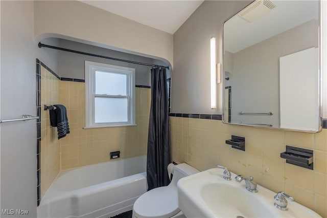 full bath with tile walls, visible vents, toilet, shower / bath combo with shower curtain, and a sink