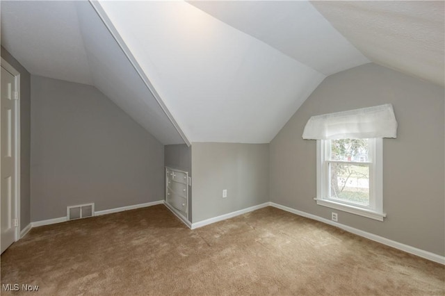 additional living space featuring lofted ceiling, baseboards, visible vents, and carpet flooring