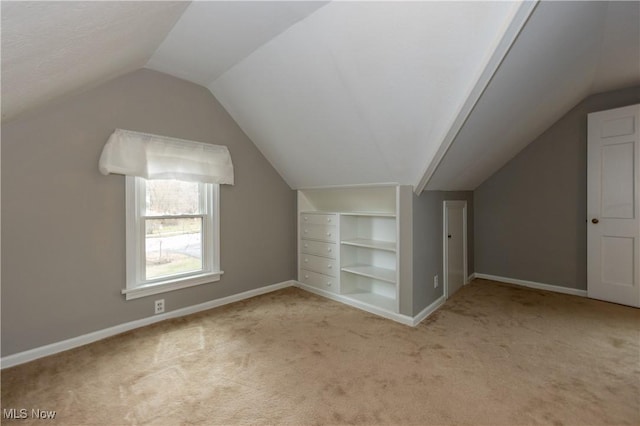 additional living space with built in shelves, lofted ceiling, carpet flooring, and baseboards