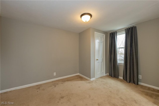 empty room featuring light colored carpet and baseboards