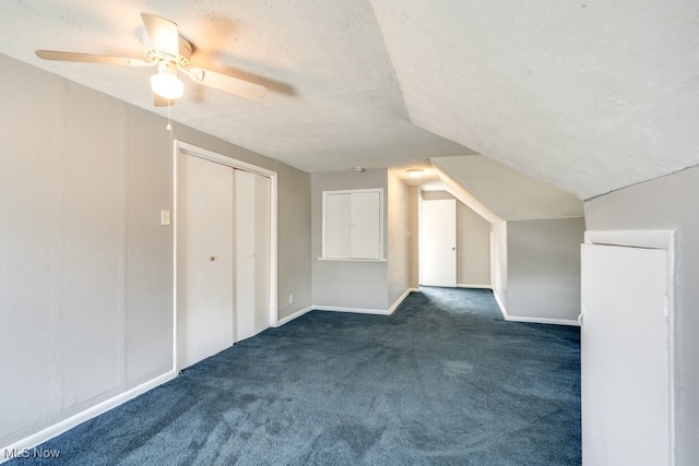 bonus room with vaulted ceiling, baseboards, dark colored carpet, and a textured ceiling