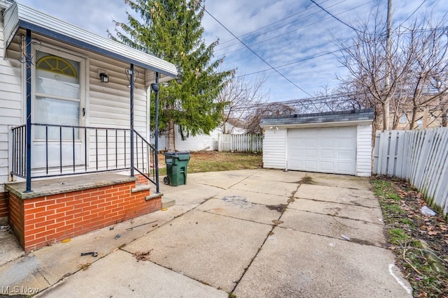 view of patio / terrace featuring a garage, fence, concrete driveway, and an outdoor structure