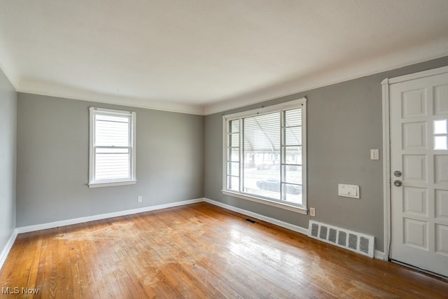 entrance foyer with crown molding, hardwood / wood-style floors, visible vents, and baseboards