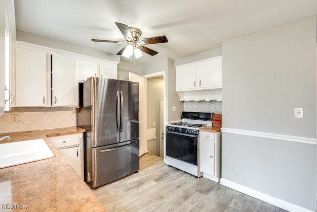 kitchen with a sink, white cabinetry, light countertops, white gas range oven, and freestanding refrigerator