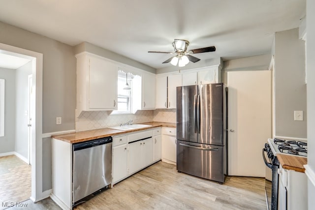 kitchen featuring stainless steel appliances, light countertops, decorative backsplash, white cabinets, and a sink