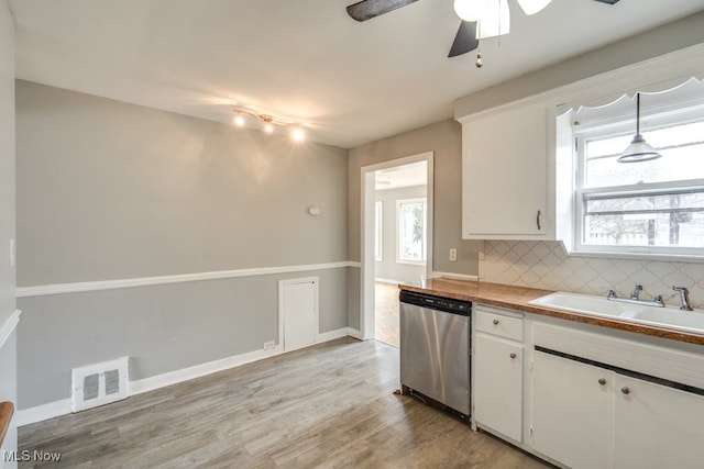 kitchen with visible vents, light wood-style flooring, decorative backsplash, stainless steel dishwasher, and a sink