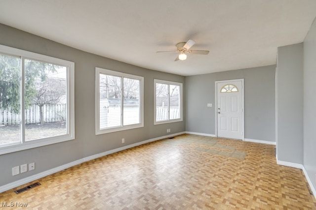 spare room with baseboards, visible vents, and ceiling fan