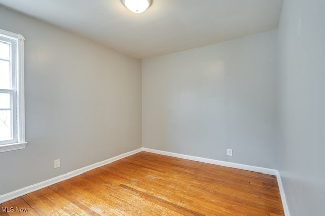 empty room featuring light wood-style floors, baseboards, and a wealth of natural light