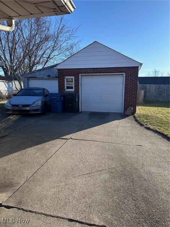 garage featuring fence and concrete driveway