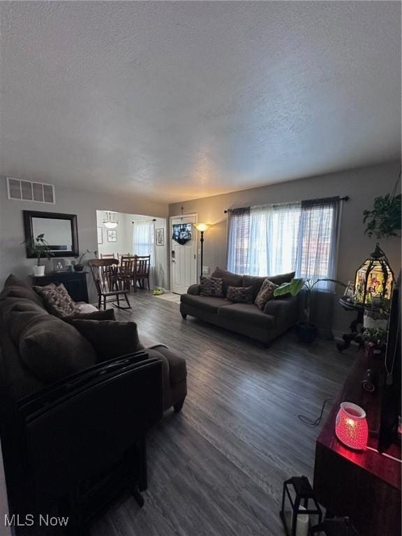 living room with a textured ceiling, a wealth of natural light, wood finished floors, and visible vents