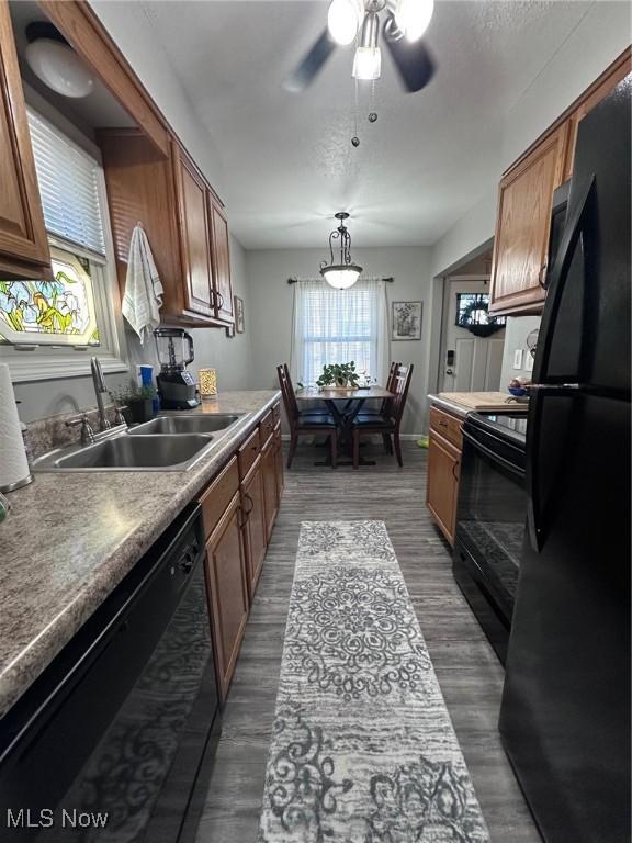 kitchen featuring black appliances, brown cabinetry, and a sink