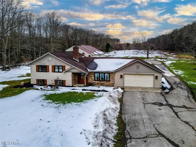 view of front of home featuring driveway, stone siding, a garage, and a chimney