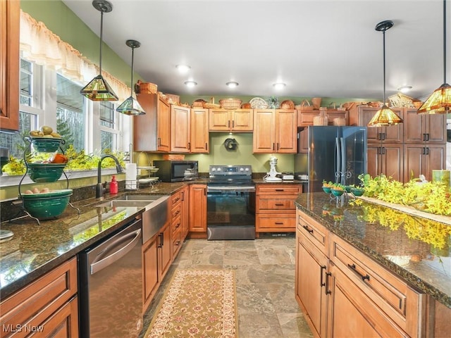 kitchen featuring stainless steel appliances, decorative light fixtures, a sink, and dark stone countertops