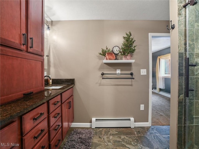 bathroom featuring a baseboard heating unit, tiled shower, vanity, and baseboards