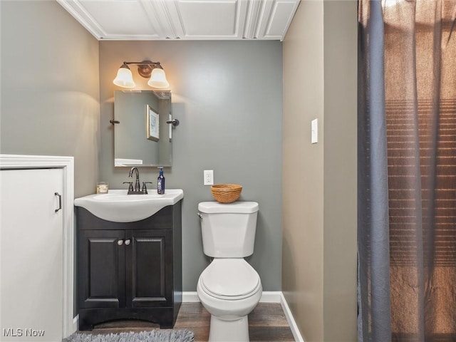 bathroom with baseboards, vanity, toilet, and wood finished floors