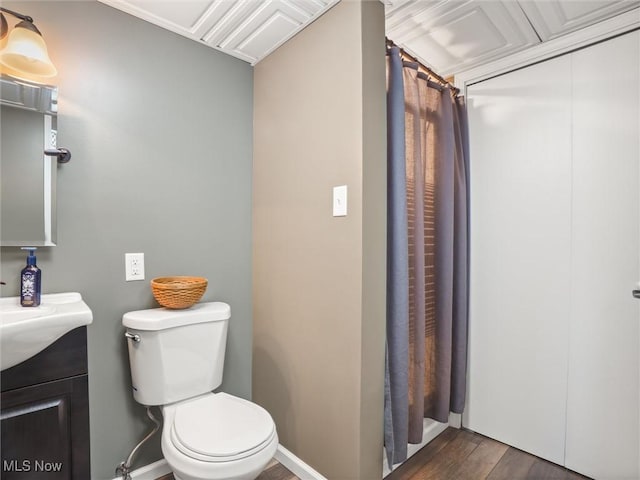 full bathroom with toilet, wood finished floors, vanity, and baseboards