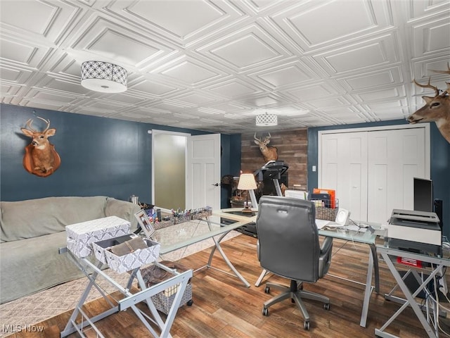 office space with an ornate ceiling, wooden walls, and wood finished floors