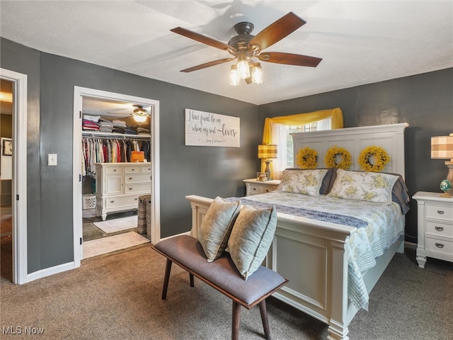 carpeted bedroom featuring a closet, baseboards, a walk in closet, and a ceiling fan