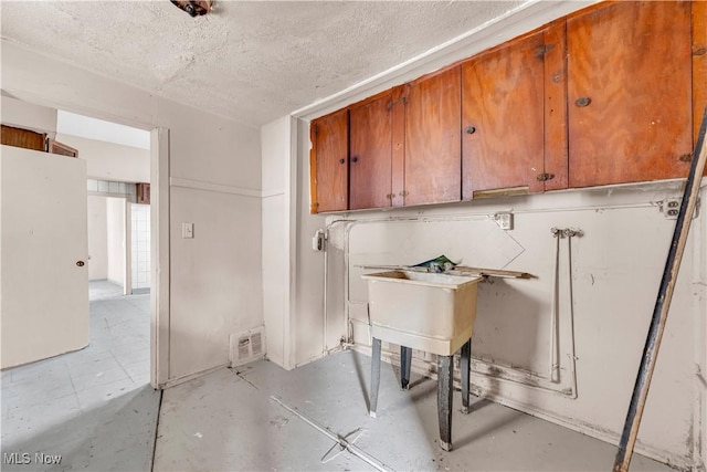 washroom with cabinet space and a textured ceiling