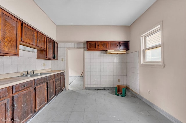 kitchen featuring baseboards, backsplash, light countertops, and a sink