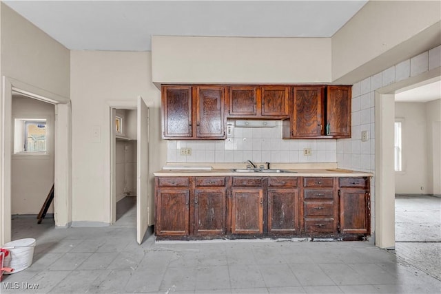 kitchen with decorative backsplash, light countertops, and a sink