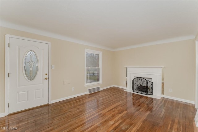 unfurnished living room featuring a fireplace with flush hearth, visible vents, baseboards, and wood finished floors