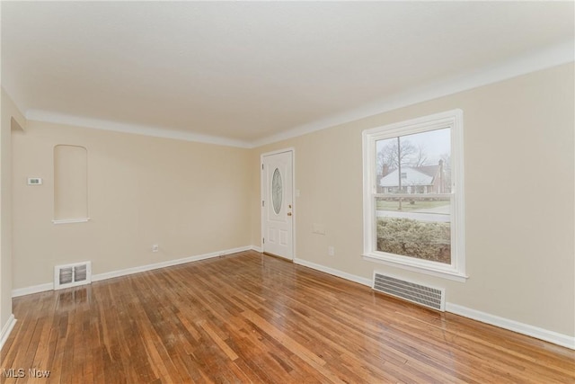 spare room with baseboards, visible vents, and wood finished floors