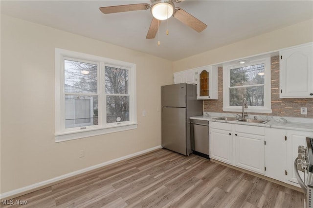 kitchen with stainless steel appliances, a sink, baseboards, white cabinets, and light countertops