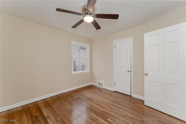 unfurnished bedroom featuring baseboards, visible vents, ceiling fan, and wood finished floors