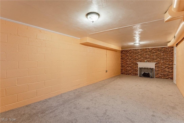 finished basement with carpet, a fireplace, and concrete block wall